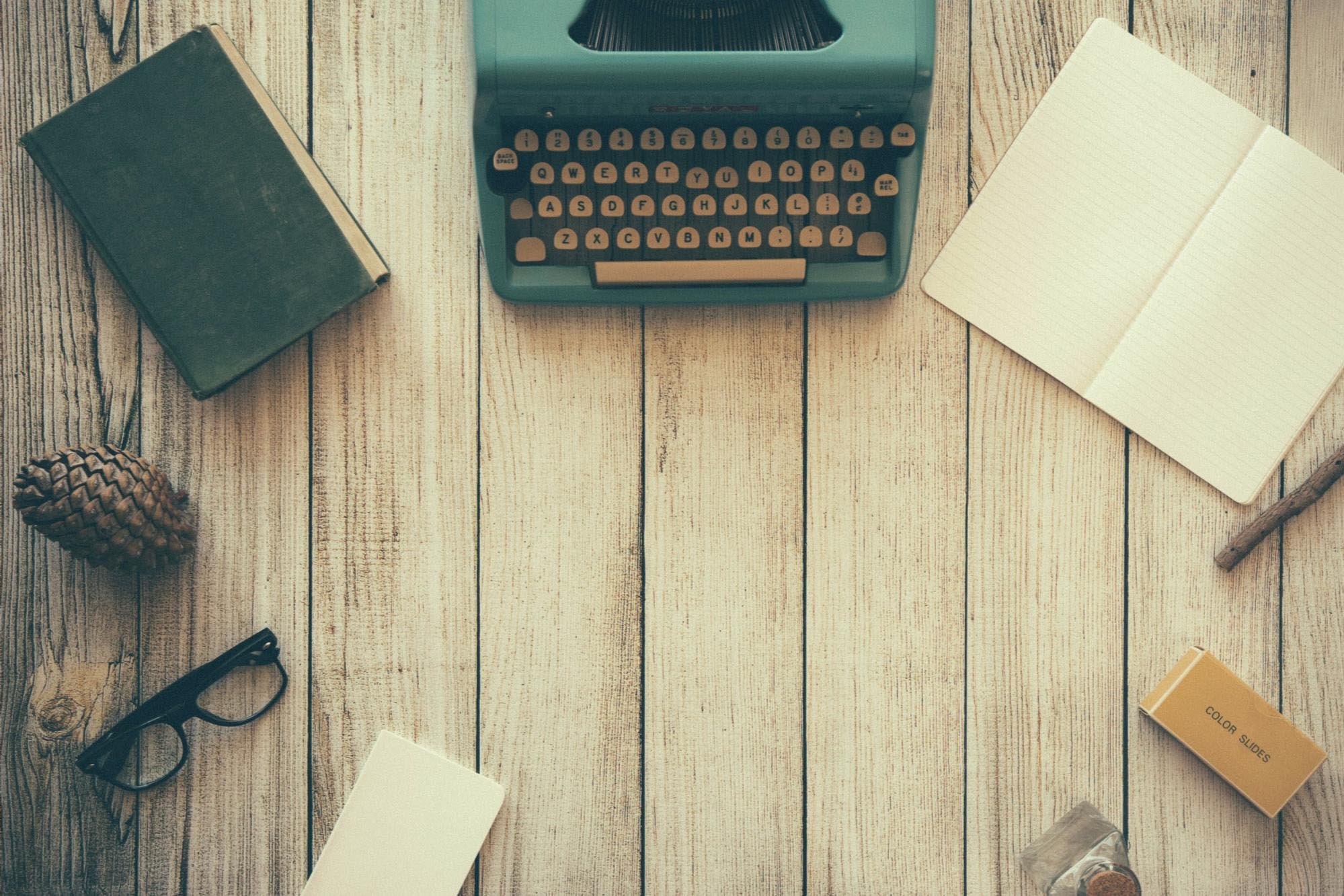 A writer's desk with book, notebook, glasses, etc.