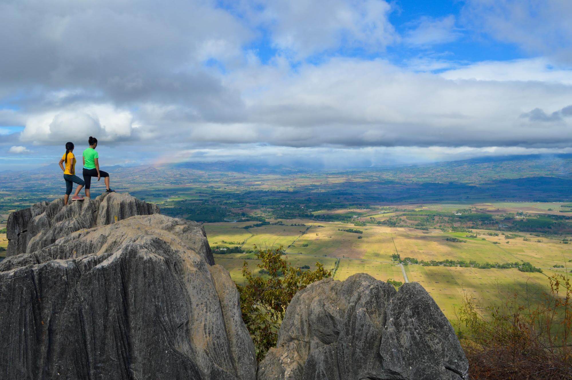Two hikers on a hilltop, surveying the vista before them