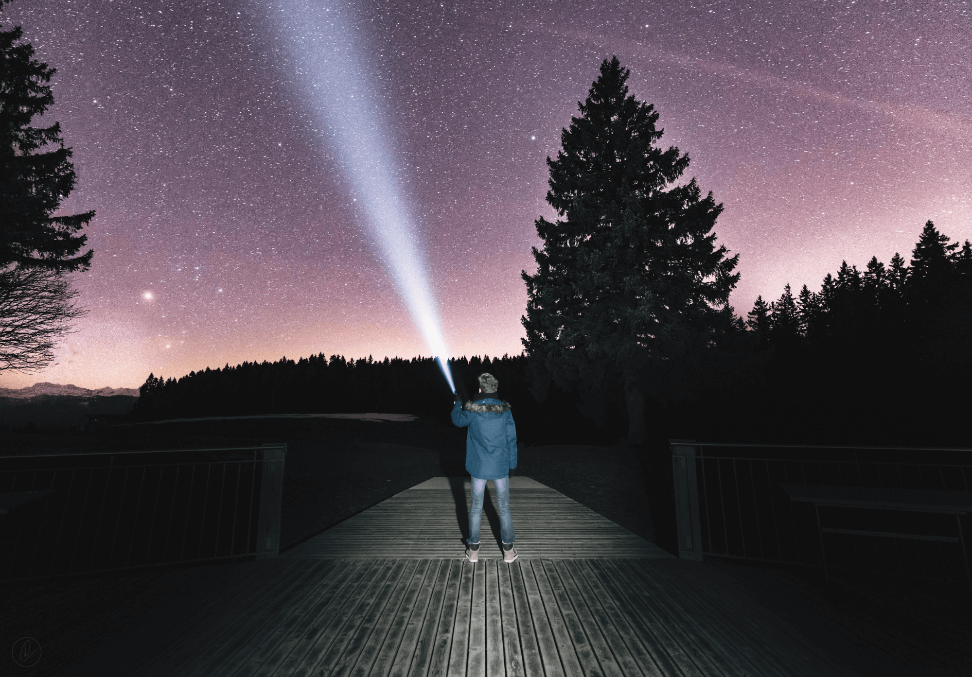 A man pointing a flashlight up at the night sky