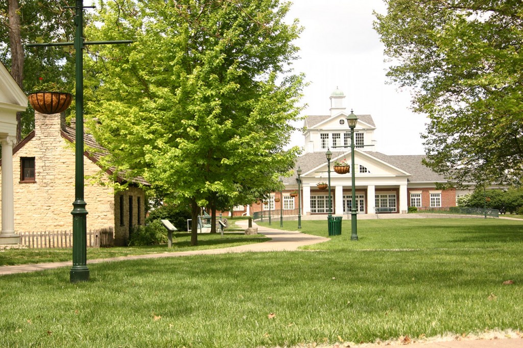 building at the end of sidewalk lined with trees and lightpoles