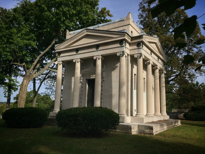 columned mausoleum surrounded by shrubs and trees