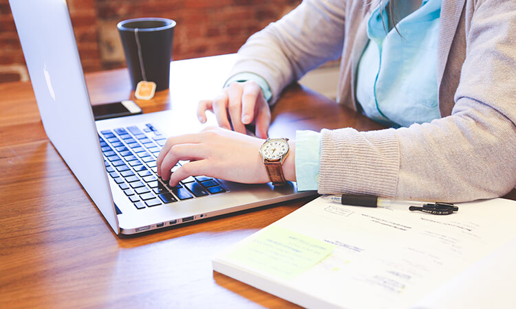 Person drinking tea while working on laptop