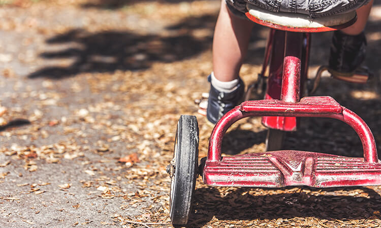 Child rides red tricycle