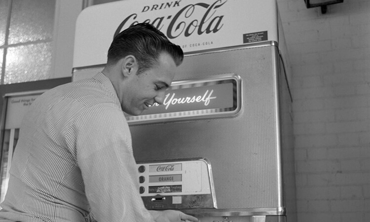 Vintage black and white photo of man at a Coca Cola vending machine