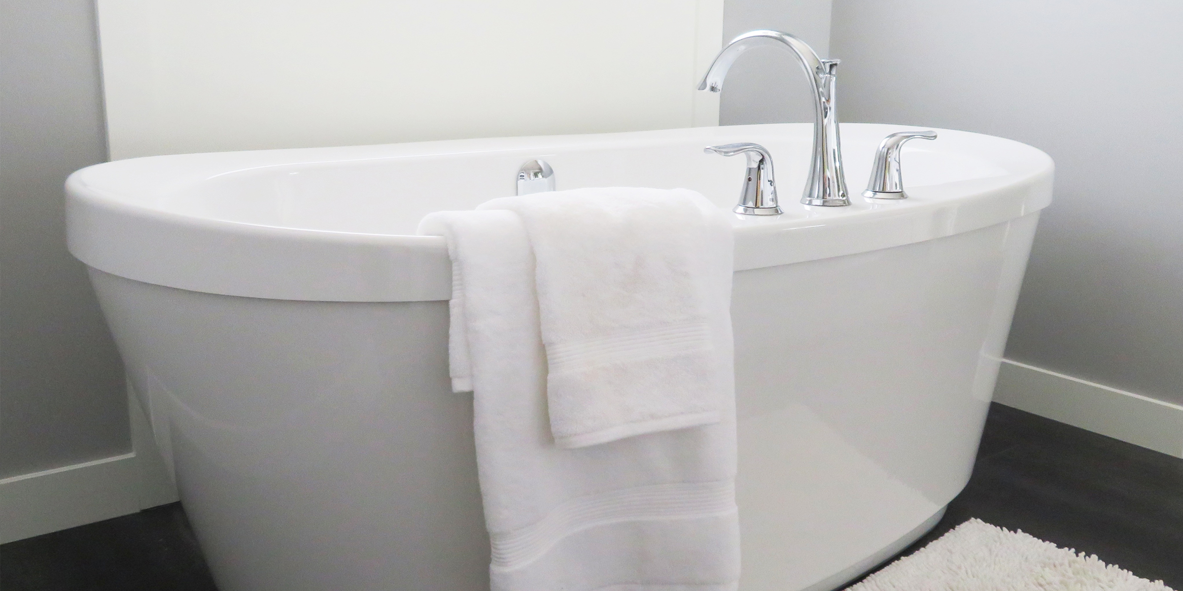 Fluffy white towel hanging on a bath tub
