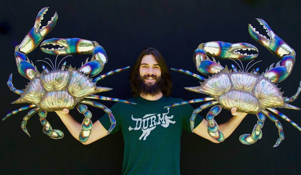 Artist Aiden Dale with two colorful chromed crab sculptures