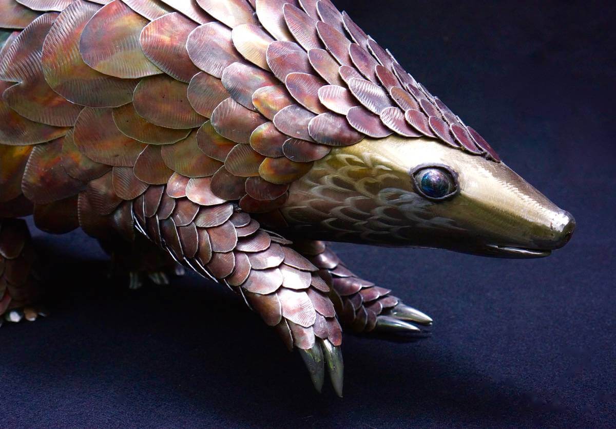 Close up of face and leg of metal pangolin sculpture